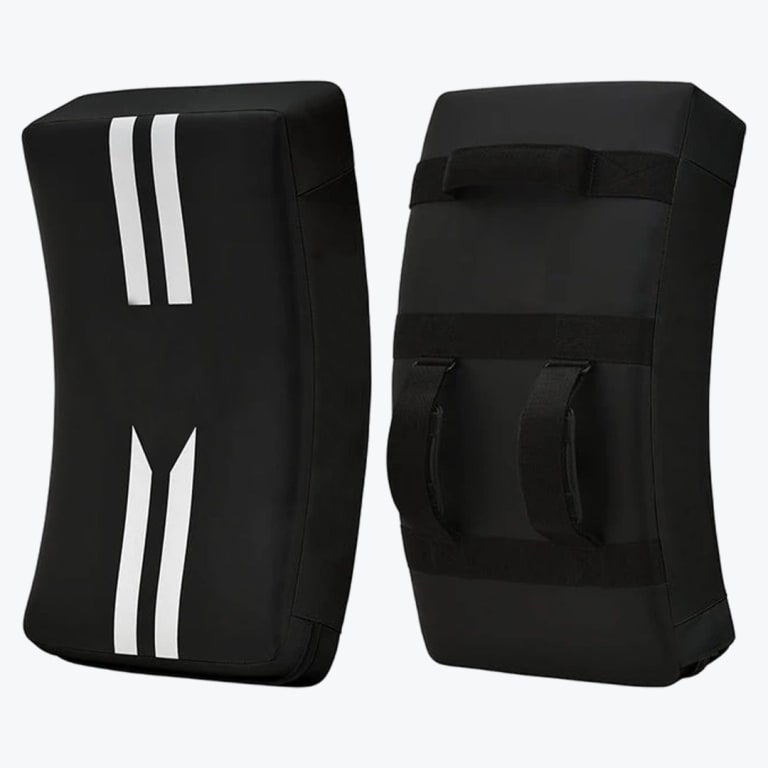 Front and back view of a pair of black curved martial arts kicking shields with white stripes on the front and adjustable straps on the back.