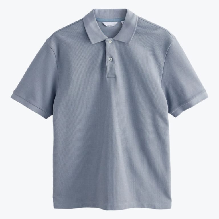 A flat lay of a light blue-grey short-sleeve polo shirt with a two-button collar against a plain white background.