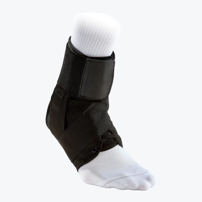 A black lace-up ankle brace with cross-straps worn over a white sock on a mannequin foot.