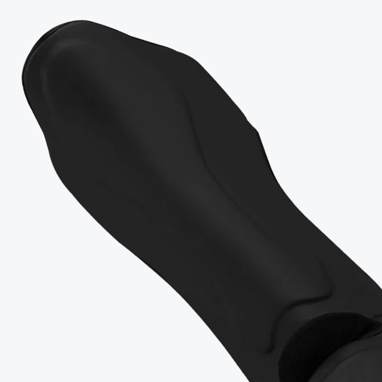 Close-up of a contoured matte black protective shin guard on a white background.
