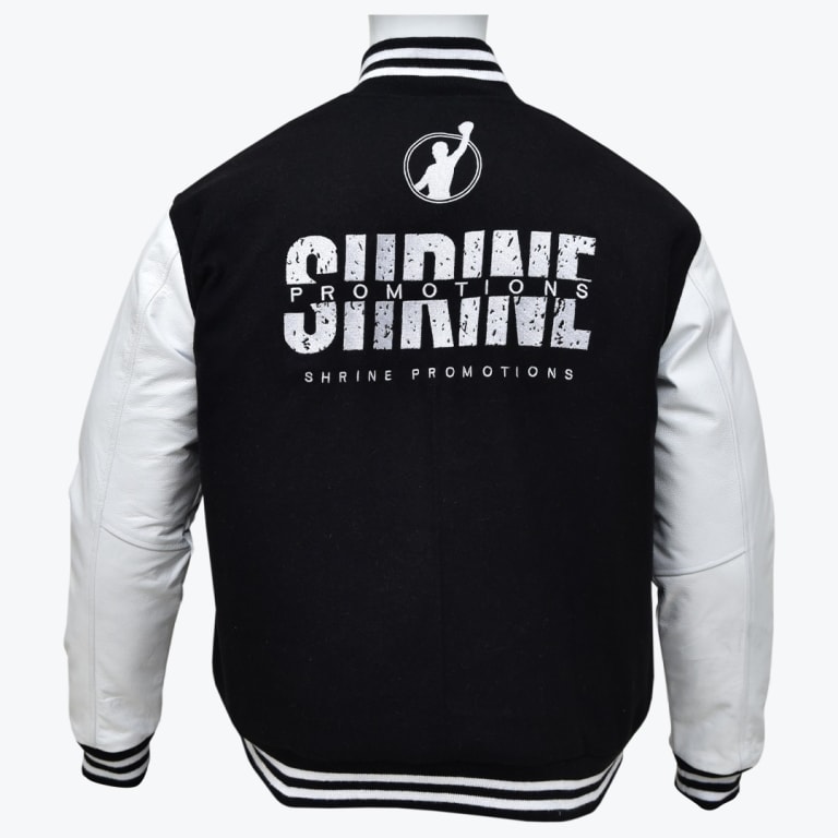 Back view of a black varsity jacket with white leather sleeves, featuring a circular logo of a silhouette with a raised arm and the text SHRINE PROMOTIONS in distressed and clean white lettering.
