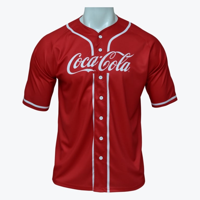 A red short-sleeved baseball jersey with white buttons, white piping, and the white Coca-Cola logo printed on the chest, displayed on a mannequin.