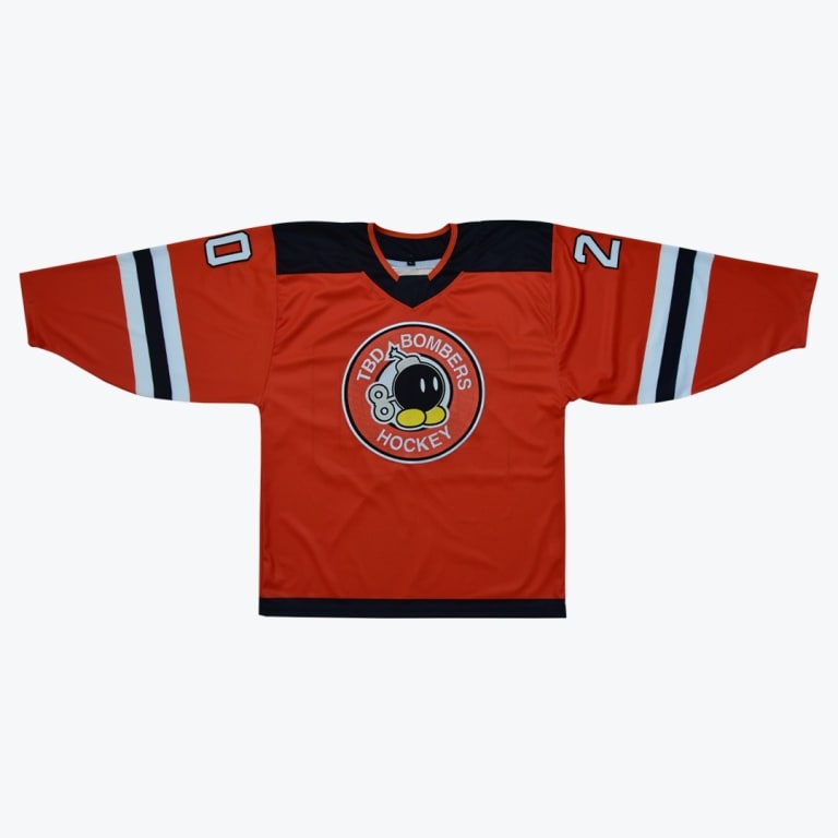 An orange hockey jersey with a cartoon bomb logo that reads TBD Bombers Hockey in the center, featuring black shoulders and striped sleeves with numbers.