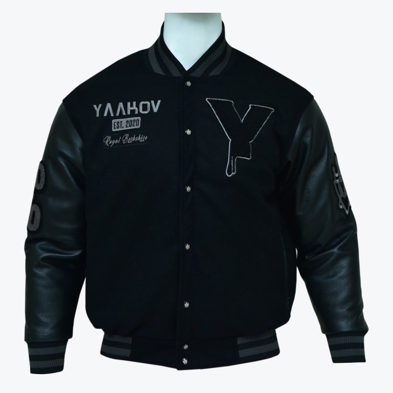 A black varsity jacket with leather sleeves, featuring a dripping Y patch and YAAKOV embroidery on a white mannequin.