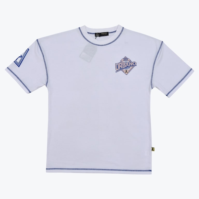 A flat-lay view of a white t-shirt with blue contrast stitching, a chest graphic reading URBANO 2001, and a sleeve logo.