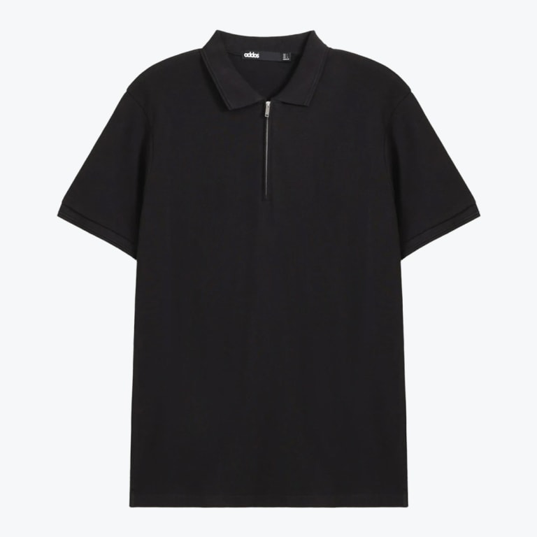 A flat lay of a black short-sleeved polo shirt with a silver half-zip collar on a white background.
