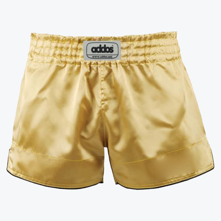 A pair of shiny gold satin boxing shorts with an elastic waistband and a grey Addos logo patch in the center, set against a plain white background.