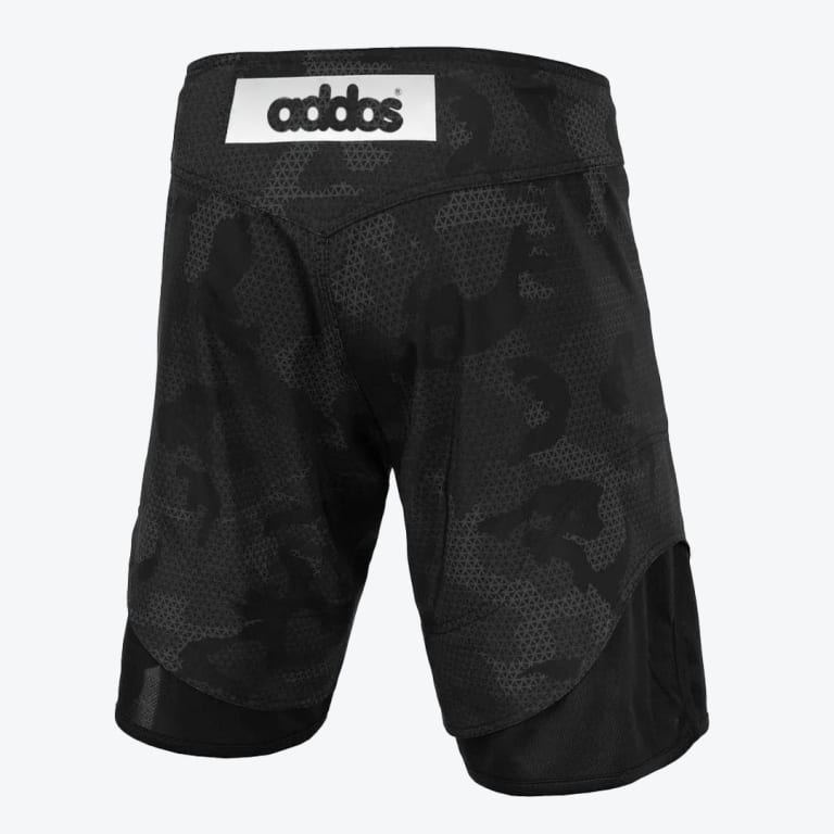 Back view of black Addos grappling shorts with a dark camouflage pattern, a white logo patch on the waistband, and black stretch panels at the hem.