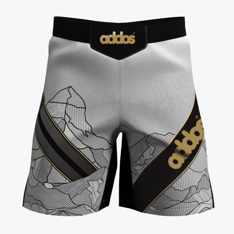 A pair of white and grey athletic fight shorts with a black waistband, featuring a detailed mountain graphic and gold addos branding.