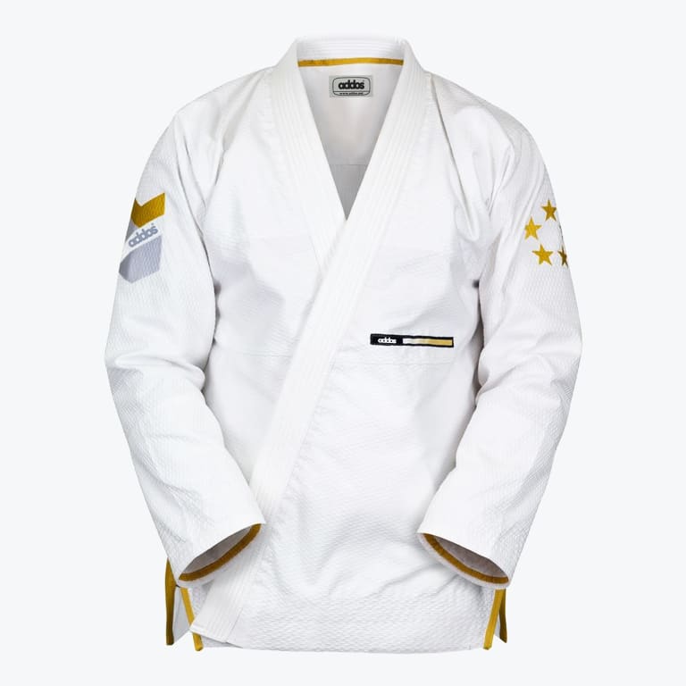 A white Addos martial arts gi jacket with gold trim, gold stars on the left sleeve, and a chevron patch on the right sleeve, displayed against a white background.