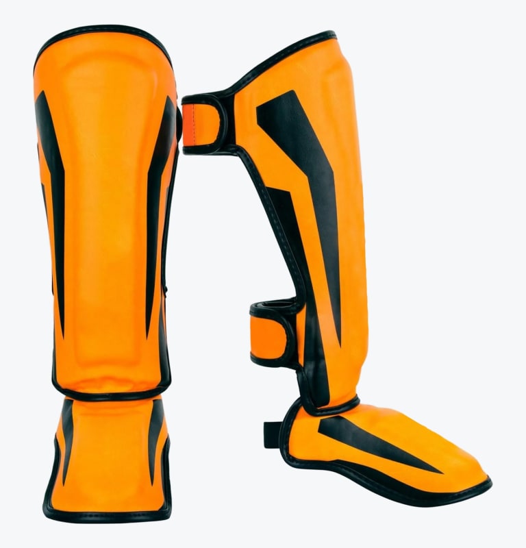 Front and side views of a pair of bright orange shin guards with black accents and instep protection, designed for martial arts training.
