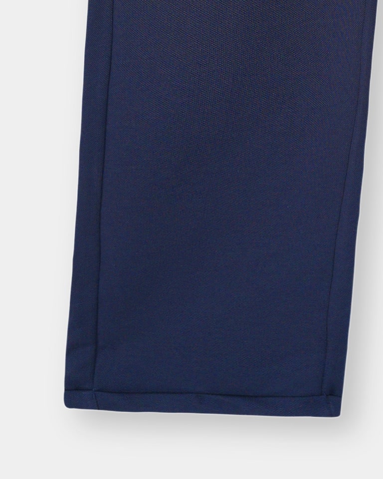 Close-up of the bottom hem of navy blue trousers, showing the textured fabric and clean stitching.