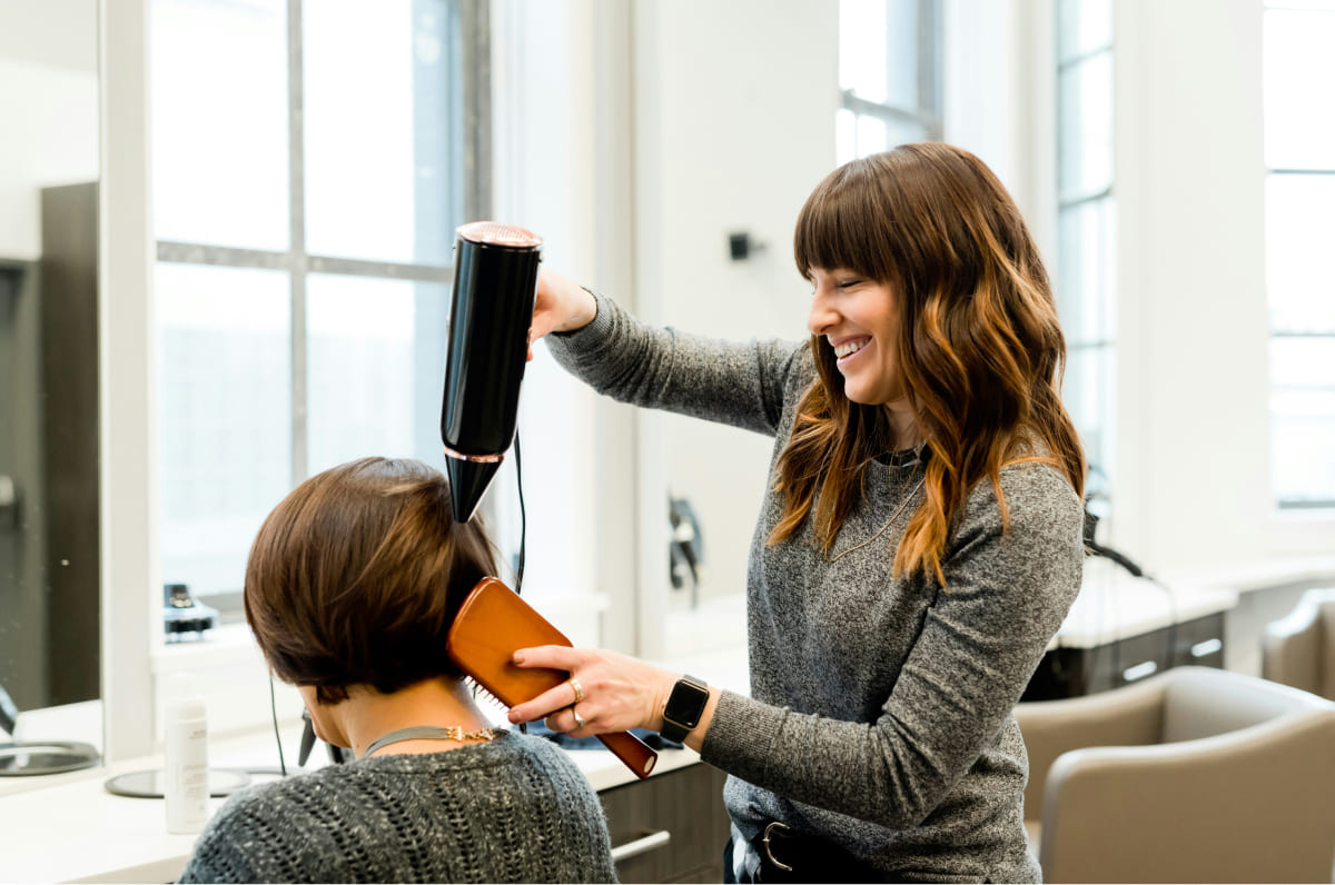 Hairdresser styling a client's hair with a blow-dryer in a salon