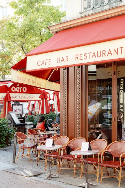 Pris de vue des chaises en rotin rouge et blanc sur la terrasse et la devanture vitrée du café de l'Aéro Passy, sur la place de Passy, dans le 16ème arrondissement de Paris
