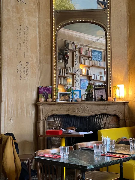 Intérieur du café La Fourmi Ailée à Paris 5, avec des tables, une cheminée et des livres aux murs