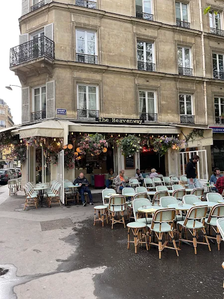 The Heavenway brasserie's terrace, with its blue-tinged rattan tables and the flowered facade visible behind them, its large windows open to the restaurant's inside.