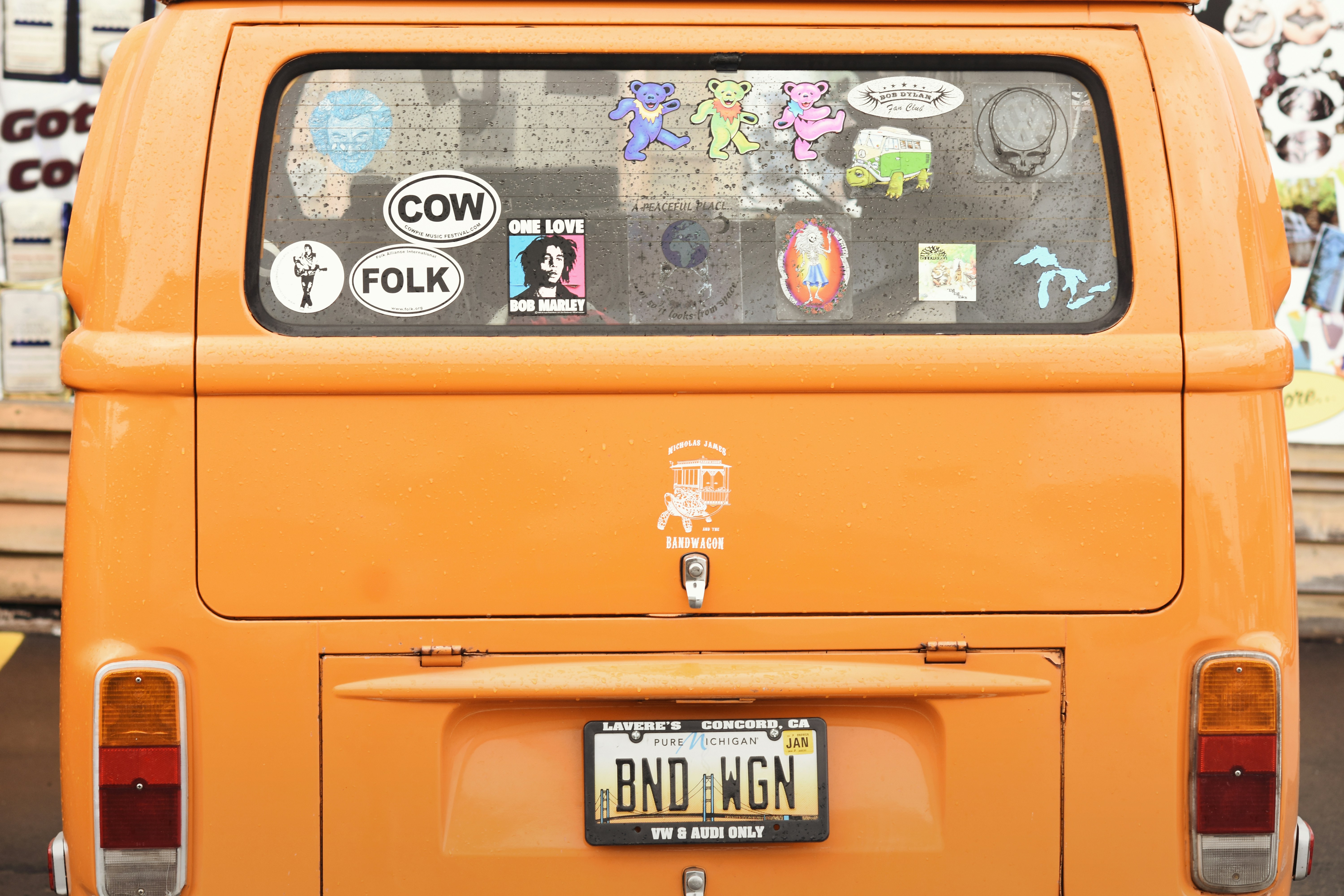 the back of a boxy orange van with rear window covered in colorful stickers