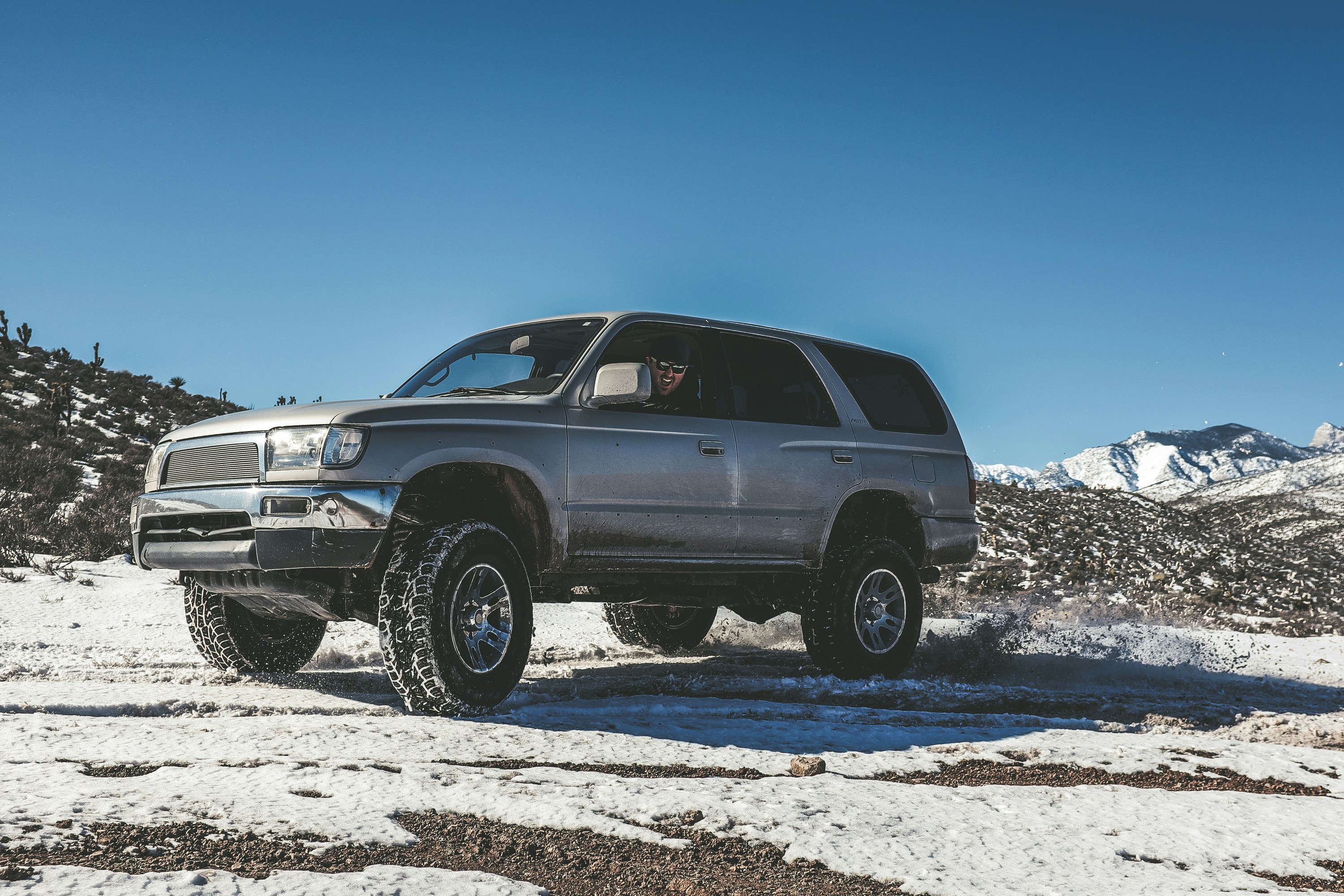 silver SUV on snowy mountain off-roading snowy tires