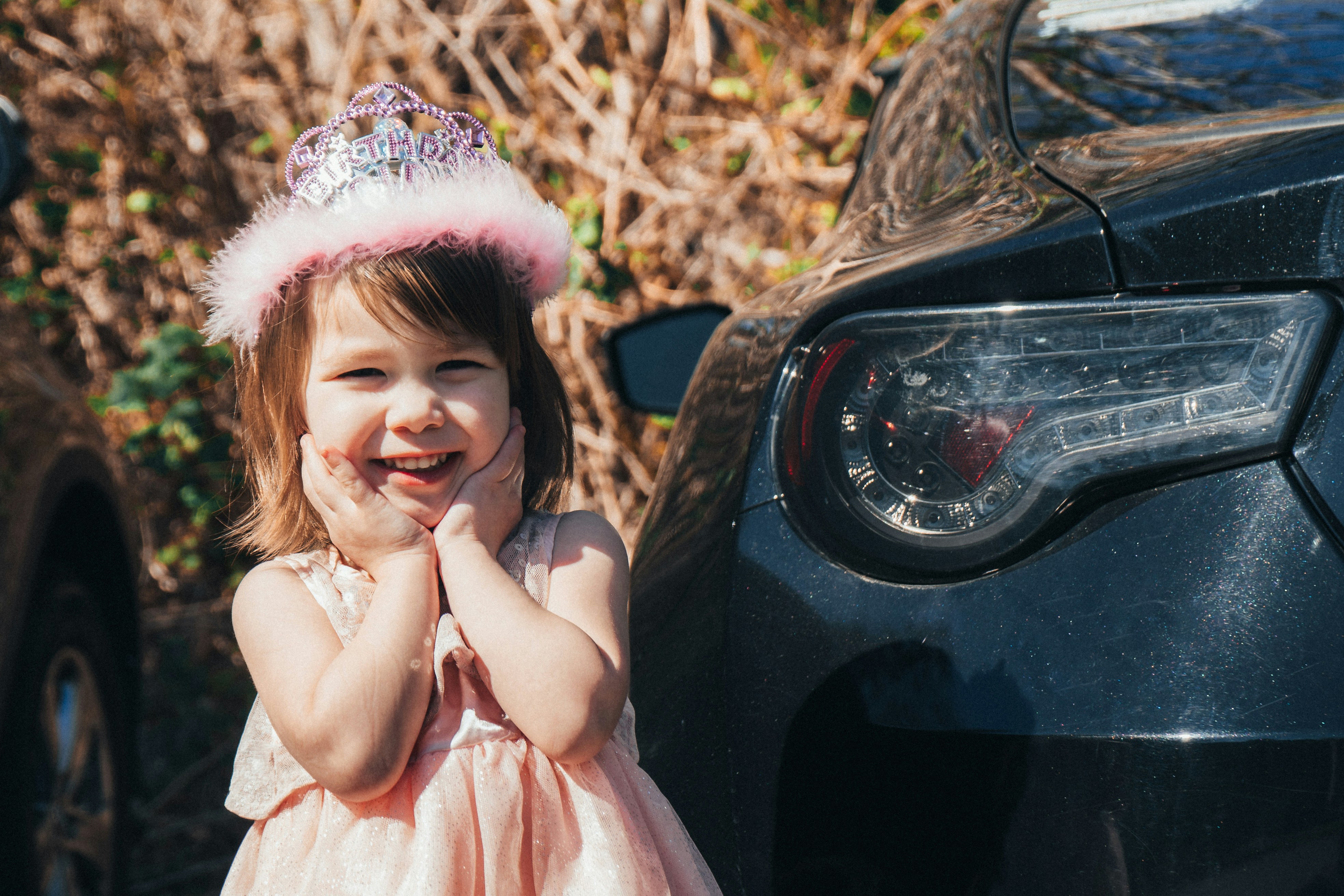 happy little girl with tiara in front of car