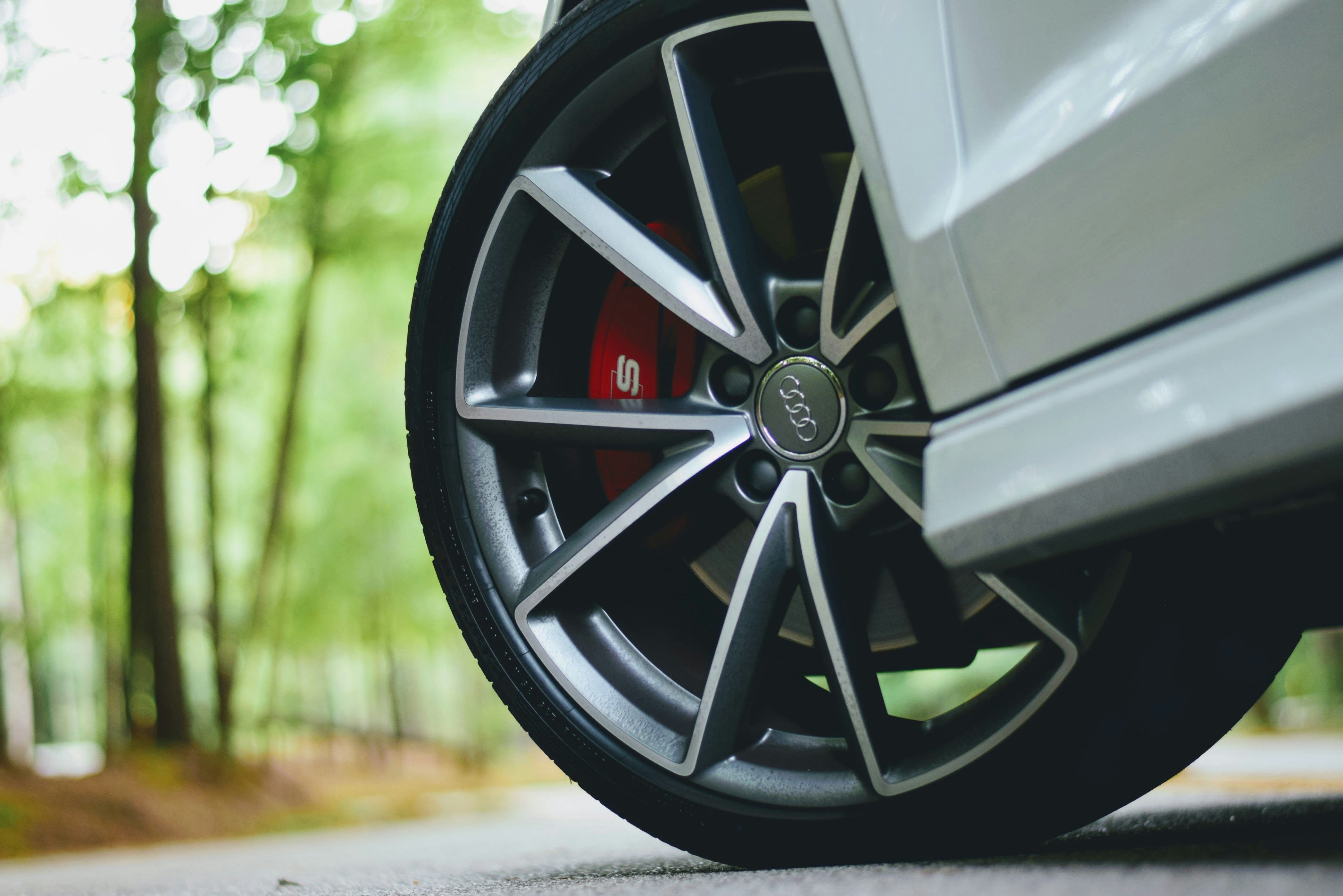 nice sporty tire on silver luxury car in woods