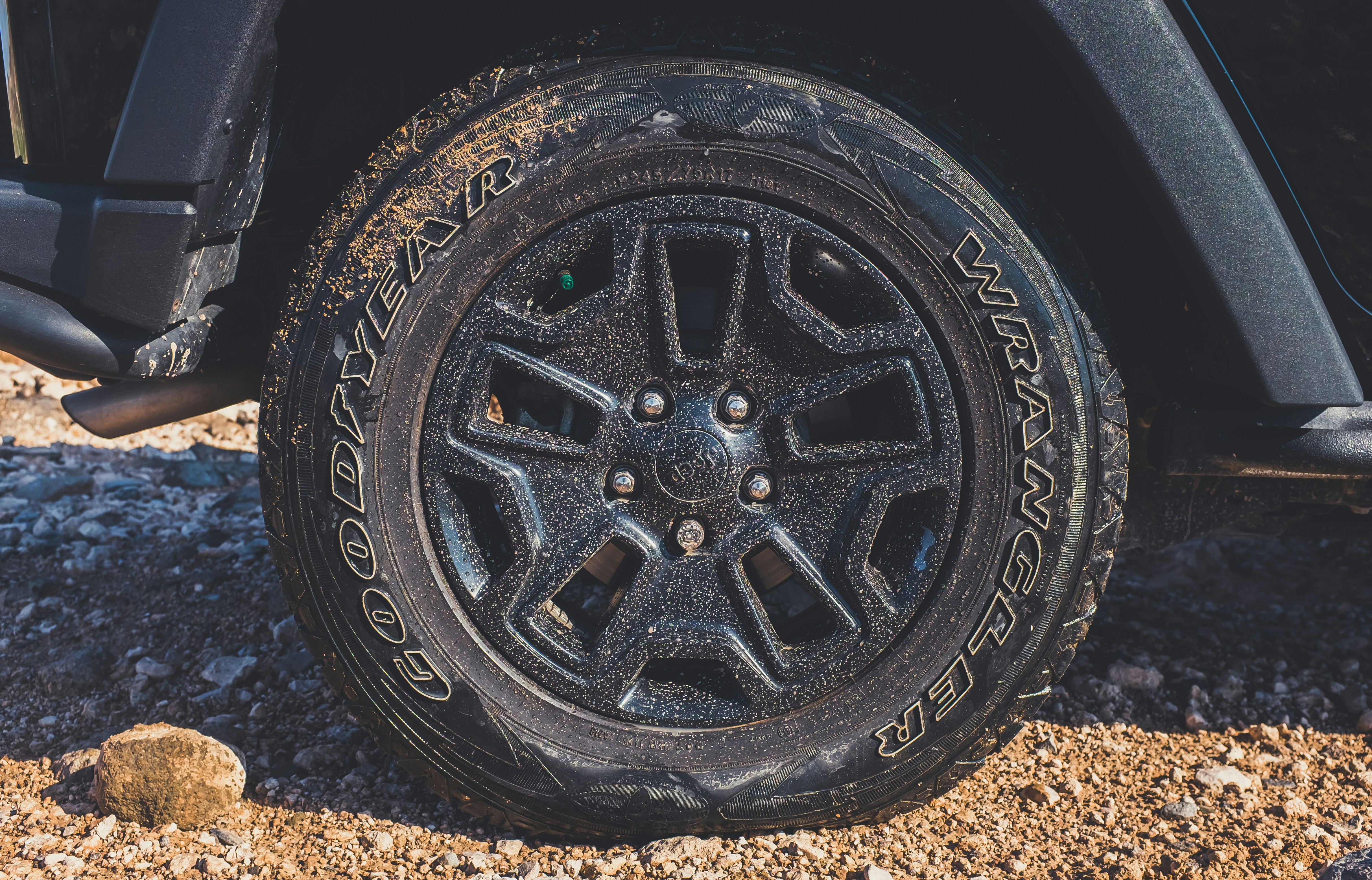 muddy old tire on dirt road in black off road vehicle or SUV