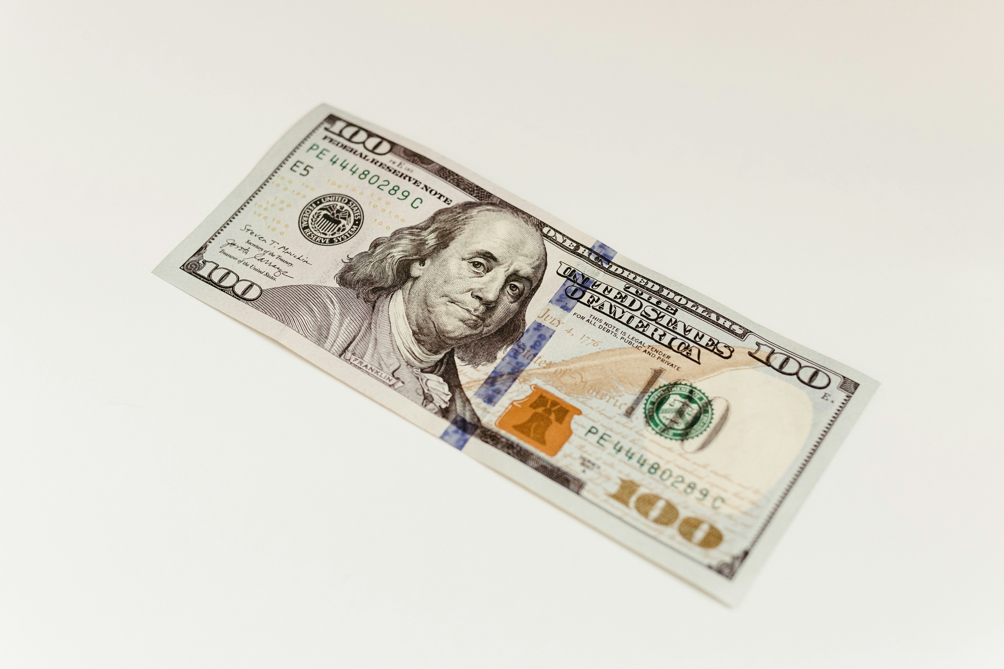 US hundred dollar bill on plain white surface