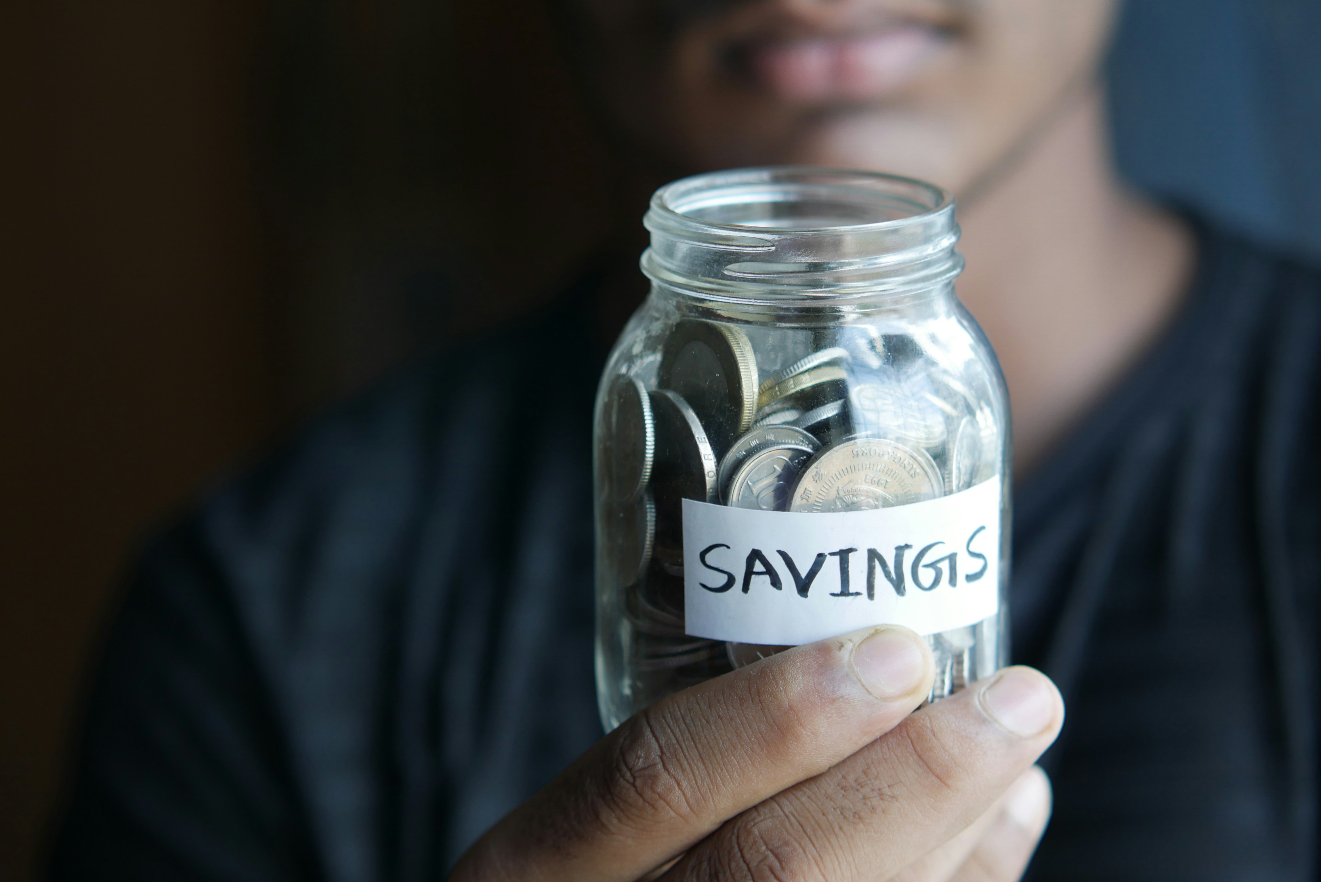 boy holding jar labeled "savings"