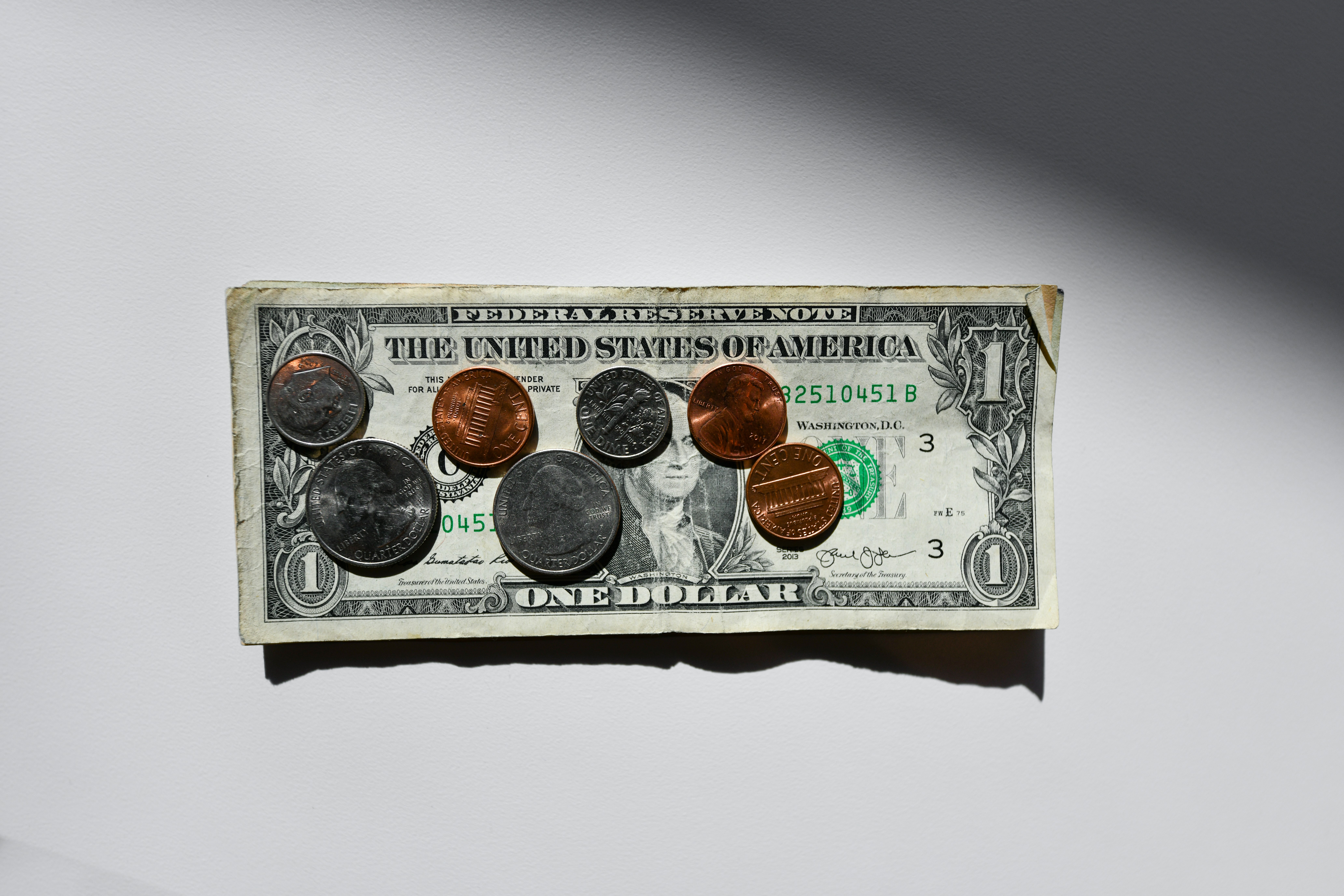 photo of US dollar bill on a white surface with loose change on it