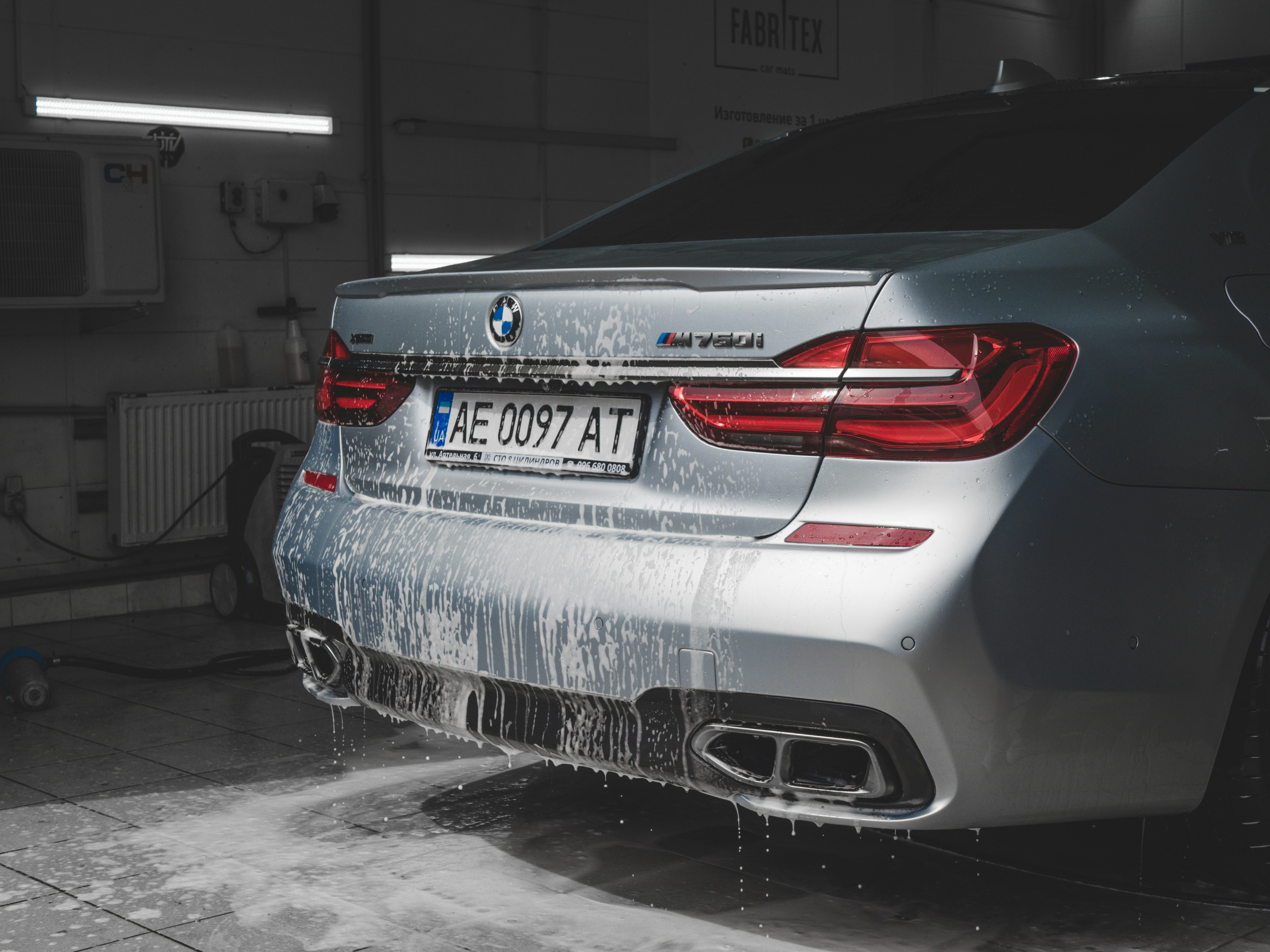 a silver BMW with soap on the back end in a garage