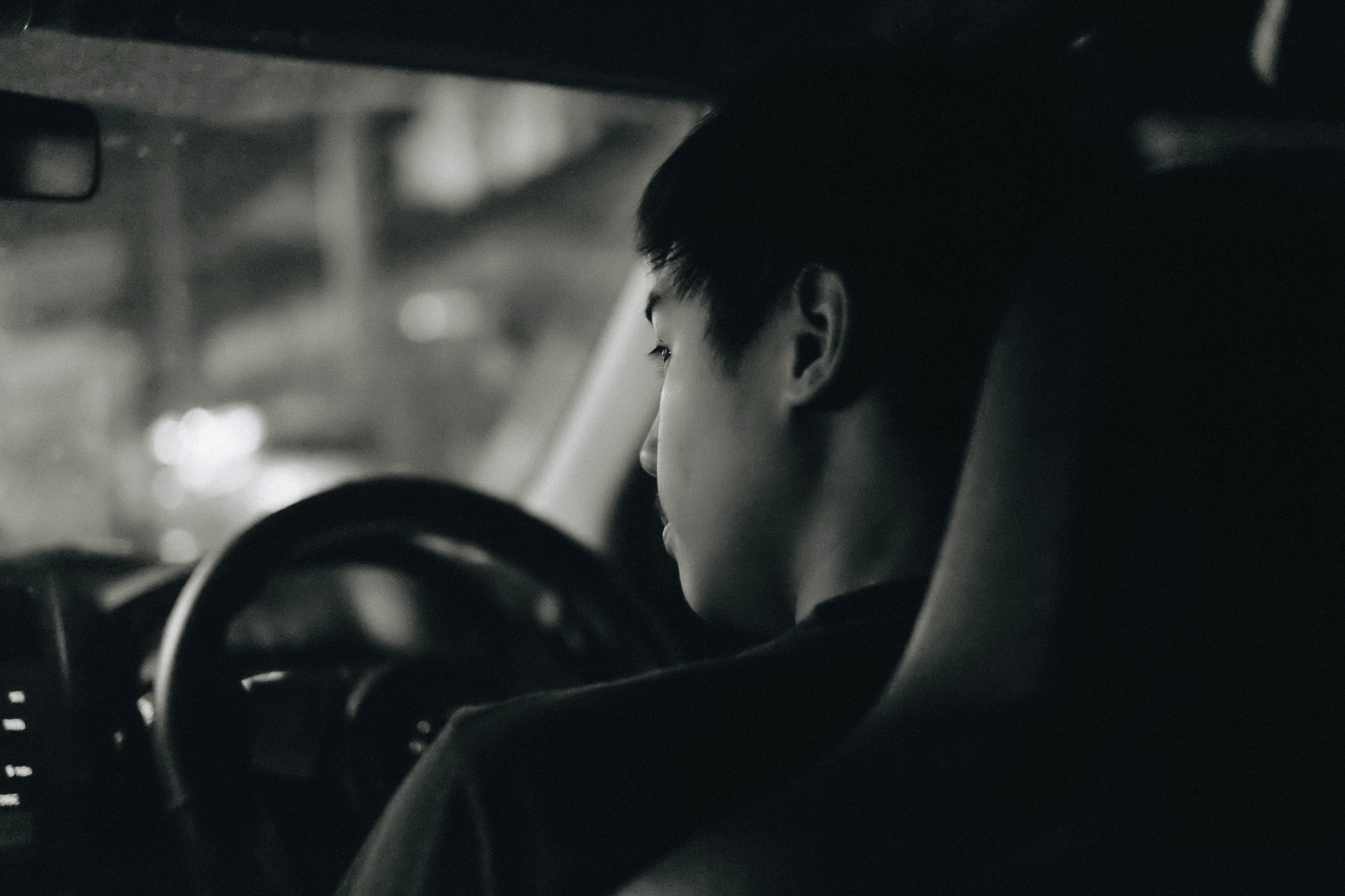 boy driving car black and white photo