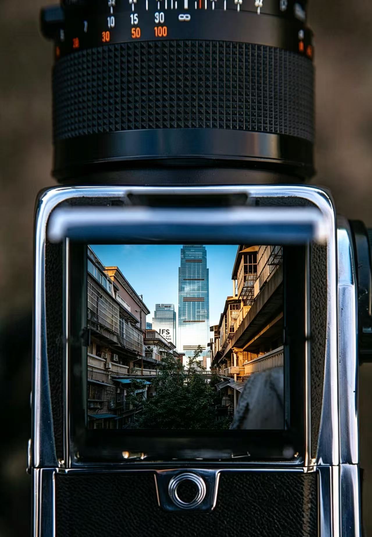Waist-level viewfinder framing old alleys against the IFS tower