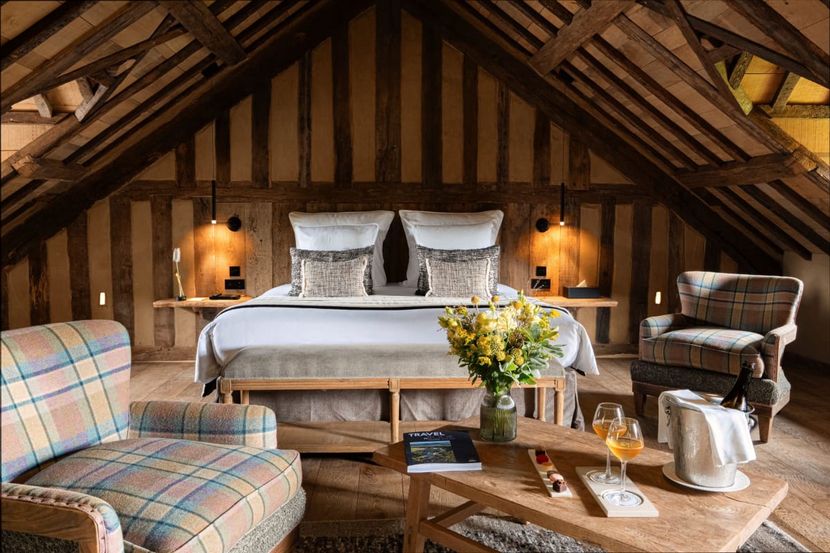 Chambre mansardée de la Ferme Saint Siméon sous les poutres et colombages, fauteuils en tartan et grand lit