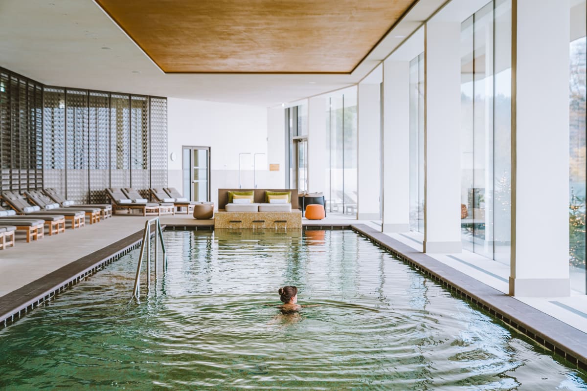 Piscine intérieure du spa du Royal Champagne Hotel & Spa, sous un plafond doré, avec baies vitrées sur la vallée