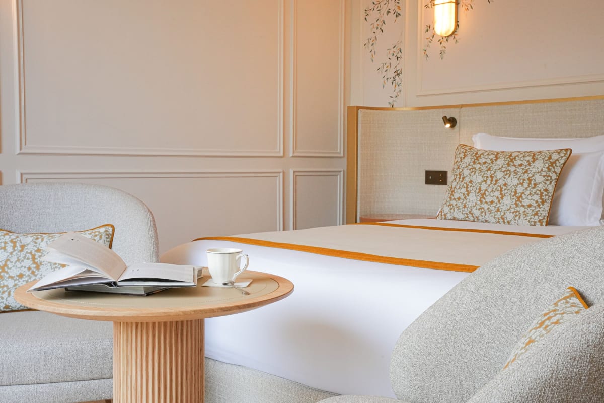 Chambre du Relais d'Amboise avec fresque de branches fleuries, coussins brodés et fauteuils bouclette