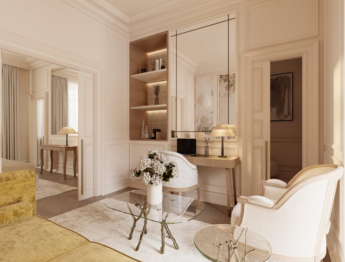 Salon d'une suite du Relais d'Amboise avec fauteuils blancs, tapis clair et bibliothèque éclairée