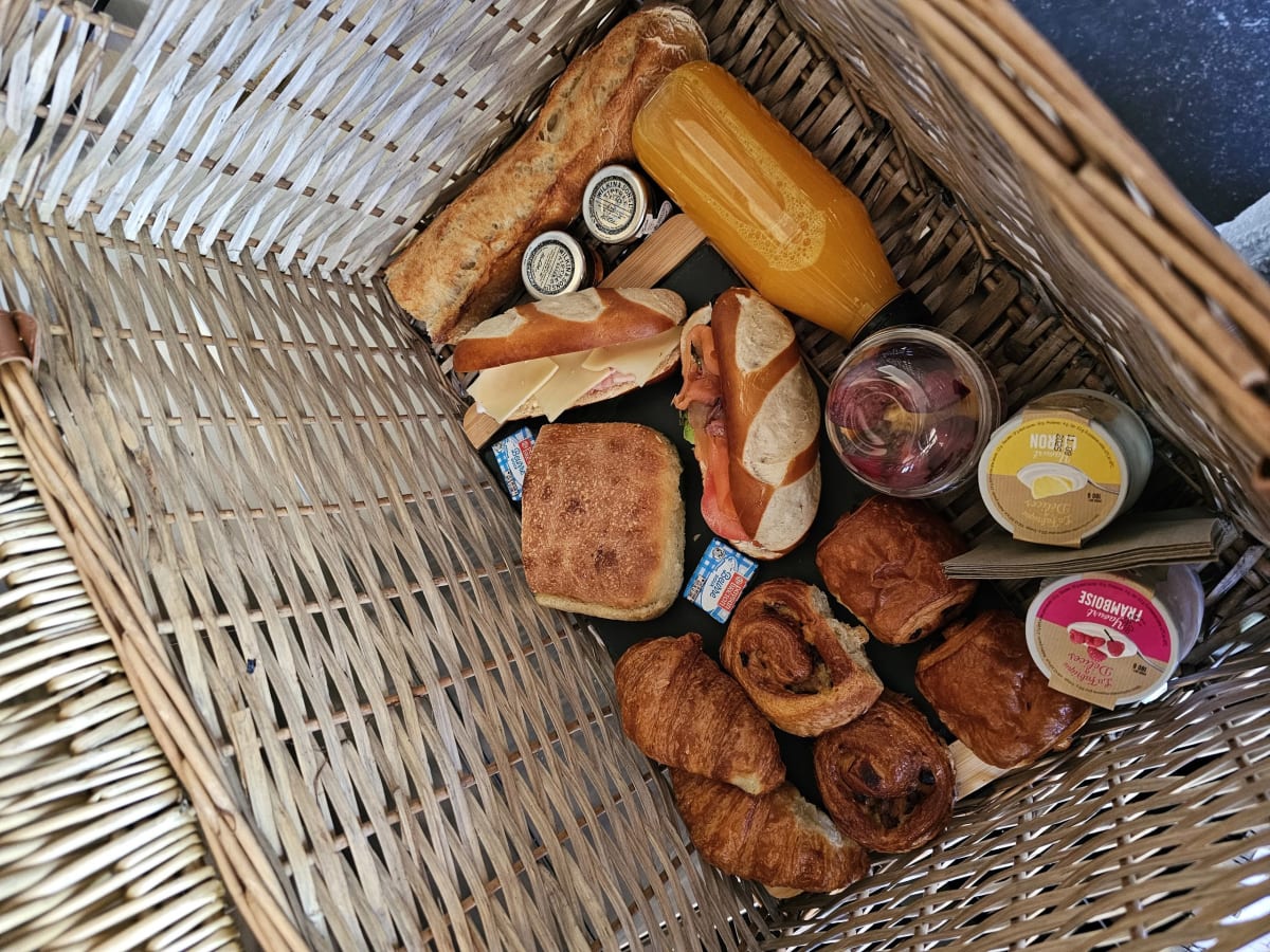 Panier du petit-déjeuner livré devant le lodge chez Pépites Lodges & Spas : viennoiseries, pain, jus et confitures