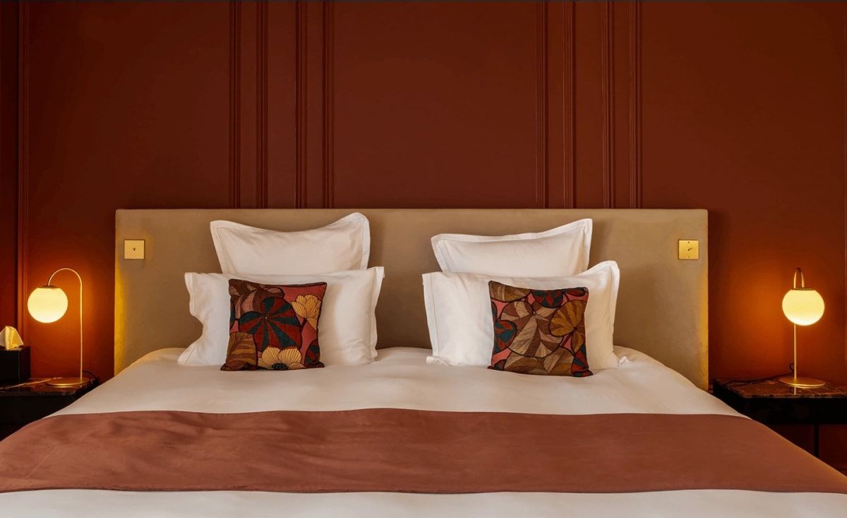 Chambre du Domaine de Rochebois aux murs terracotta, grand lit et coussins brodés