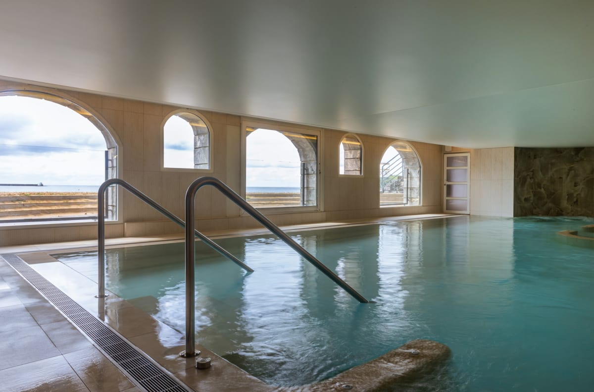 Piscine intérieure d'eau de mer chauffée du Grand Hôtel Spa & Thalasso, avec des baies en arcades ouvertes sur l'océan