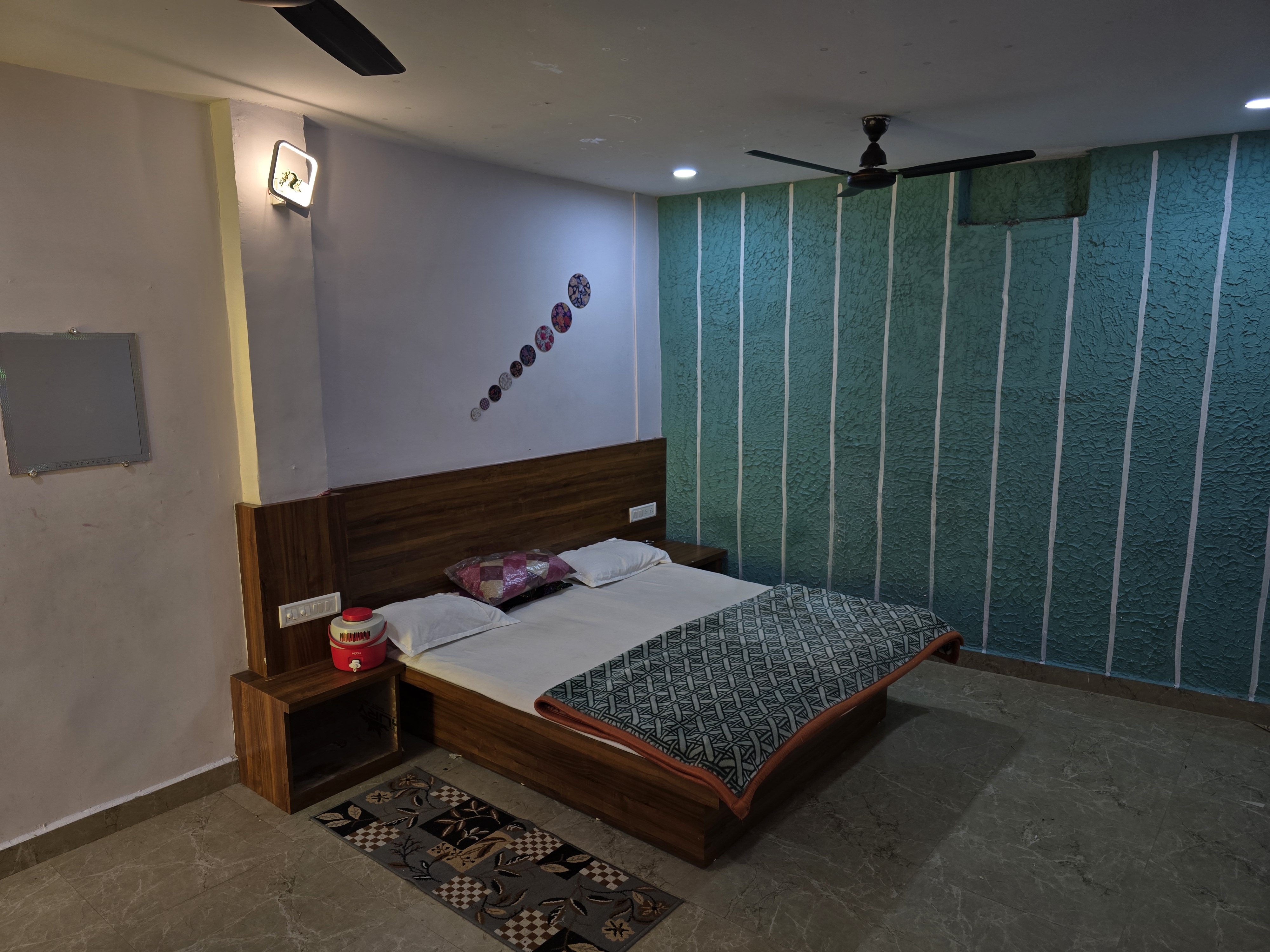 Double-bed room with teal textured wall at Mahaveer Home Stay