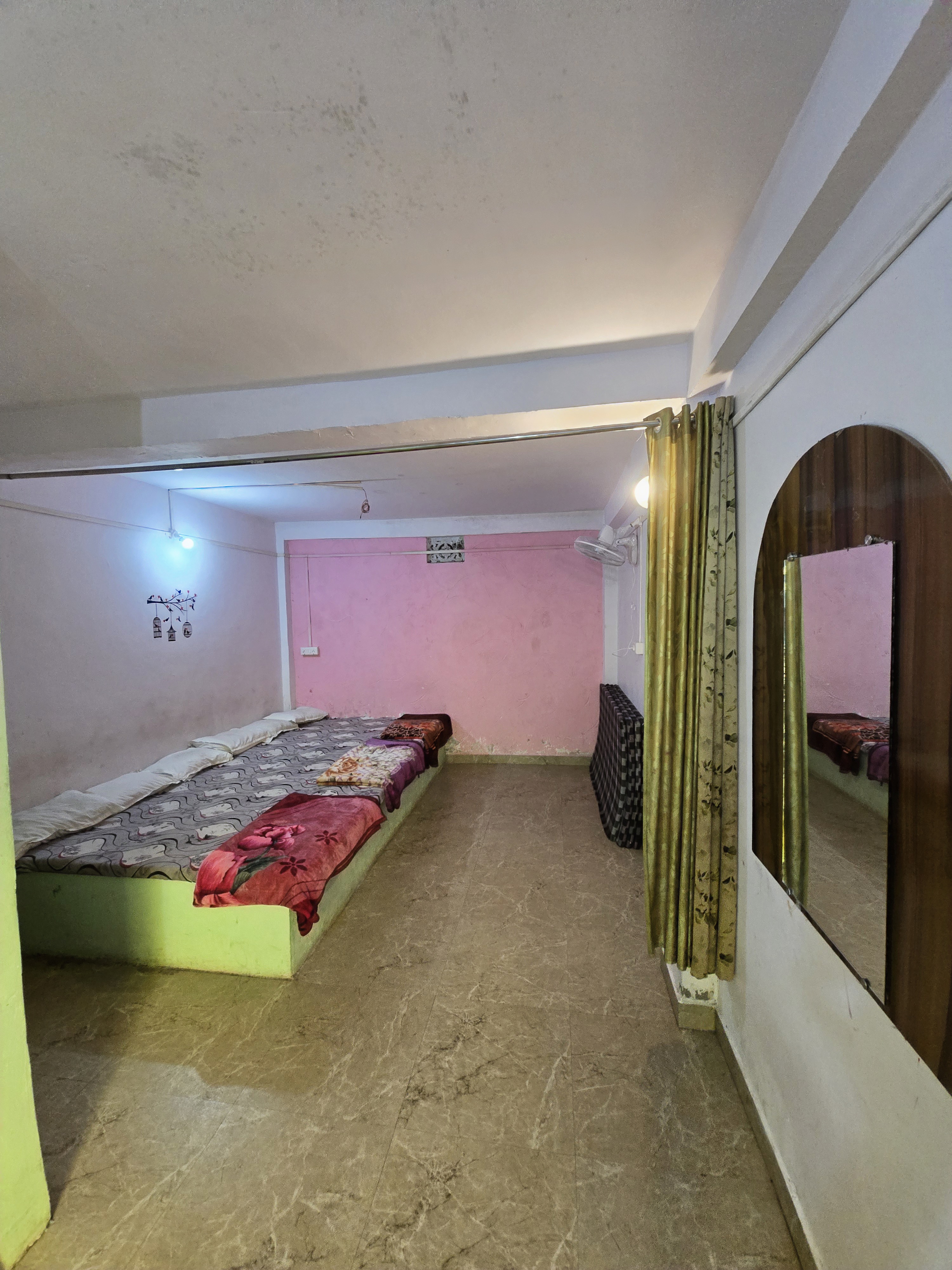 Wide view of a family room with mirror and spare mattresses at Mahaveer Home Stay
