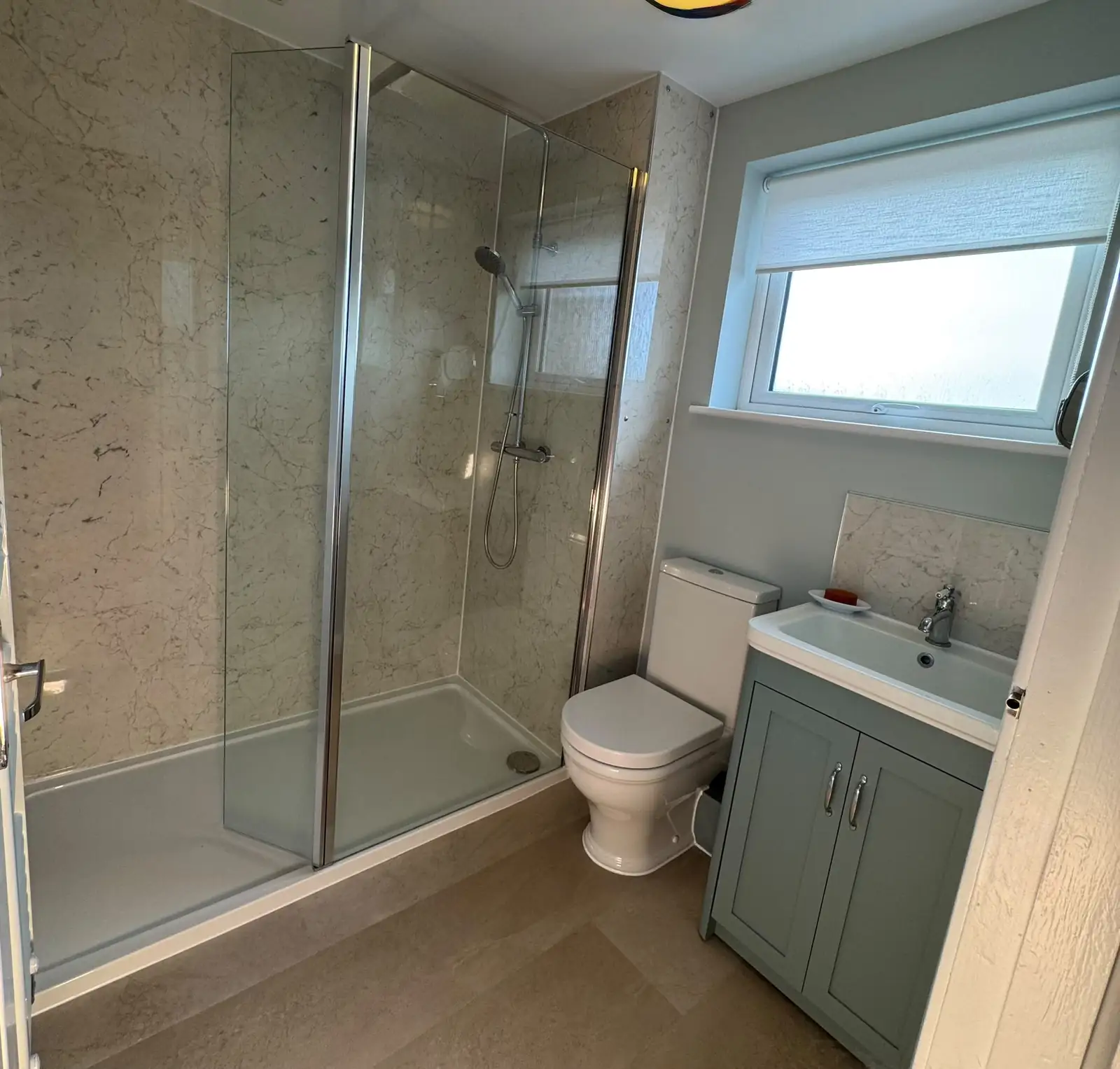 Finished bathroom with a glass shower enclosure, toilet and vanity unit