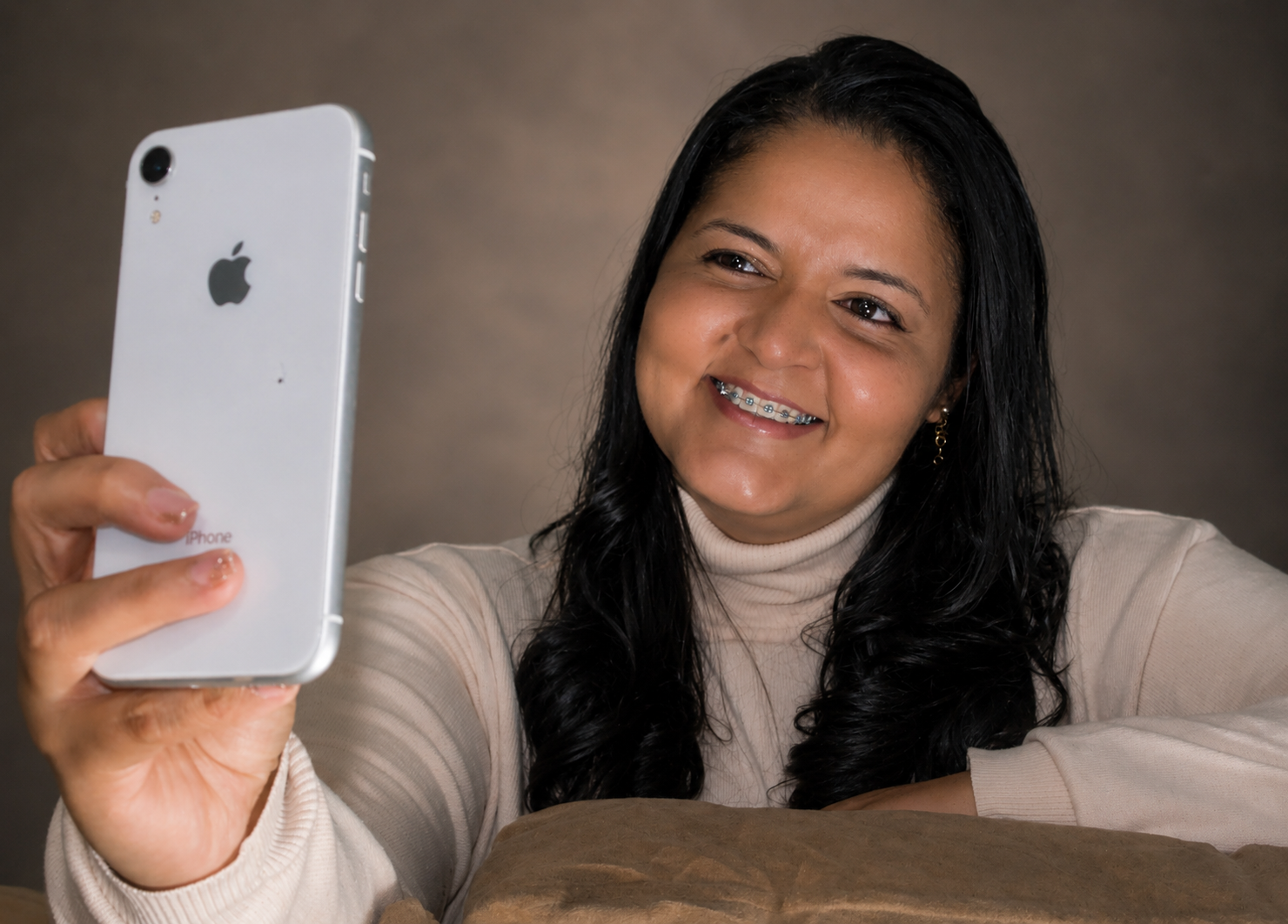 Vanessa Barros sorrindo enquanto segura um smartphone