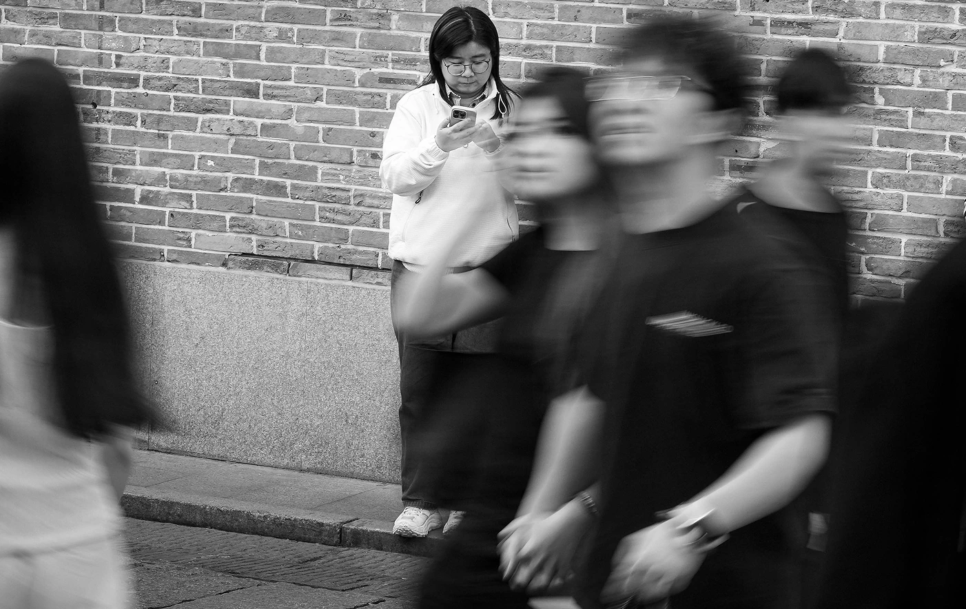 砖墙前站立的人与经过的人群