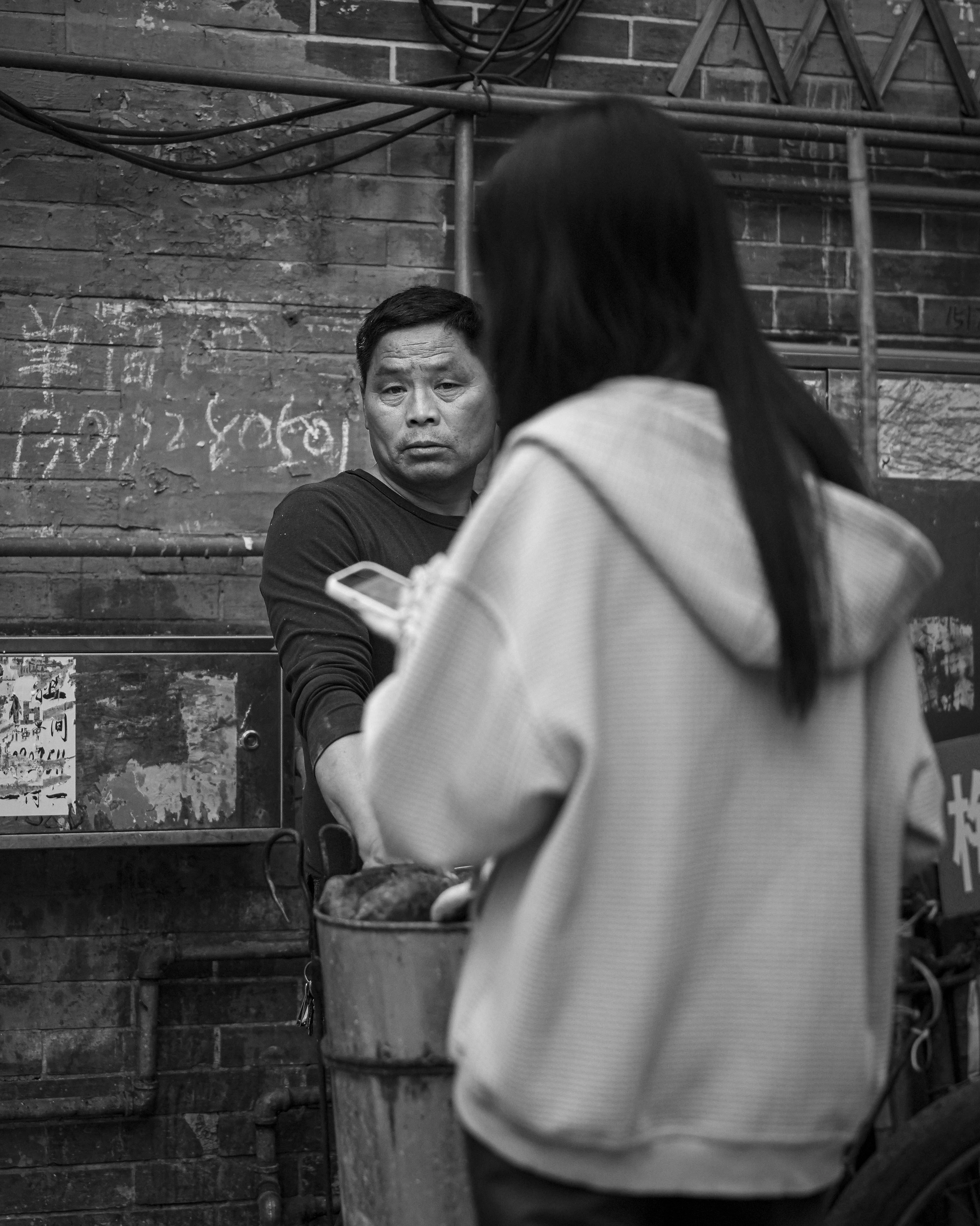 砖墙前看向镜头的男子