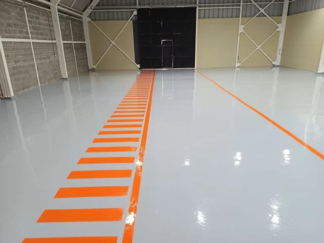 Piso epóxico gris con demarcación naranja en taller mecánico de Temuco