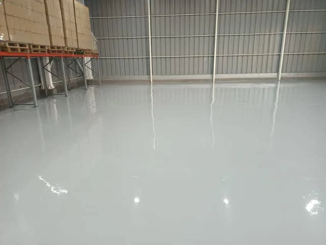 Piso epóxico gris brillante en bodega de vinos con racks industriales