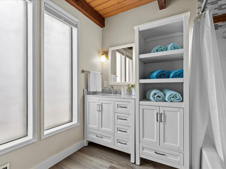 Bright bathroom with vanity, built-in linen storage and cedar ceiling detail