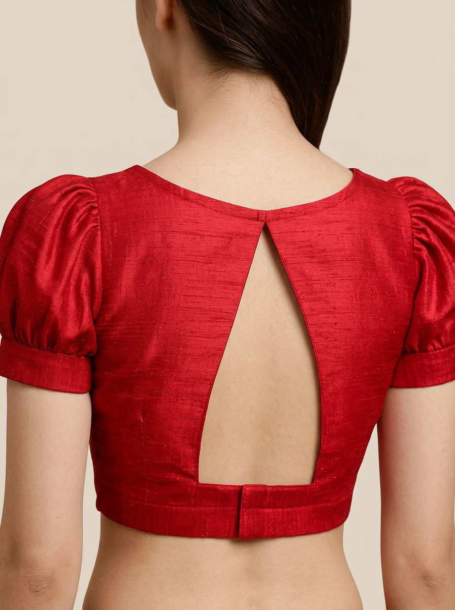 Back view of the red art silk blouse on a model, showcasing the high neck and striking triangular open back design.