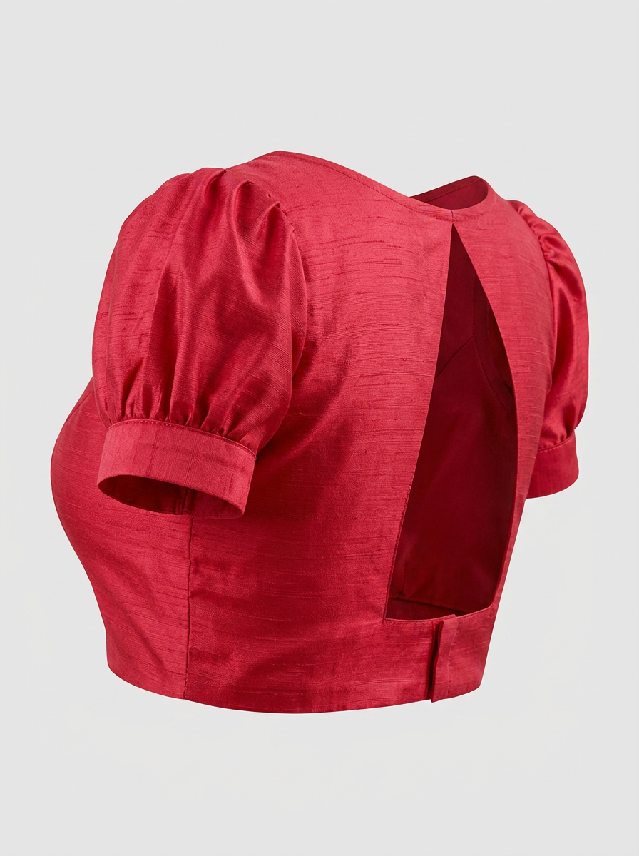Side-back angle of the red art silk blouse, highlighting the volume of the puffed sleeves and the elegant open back with its hook closure.