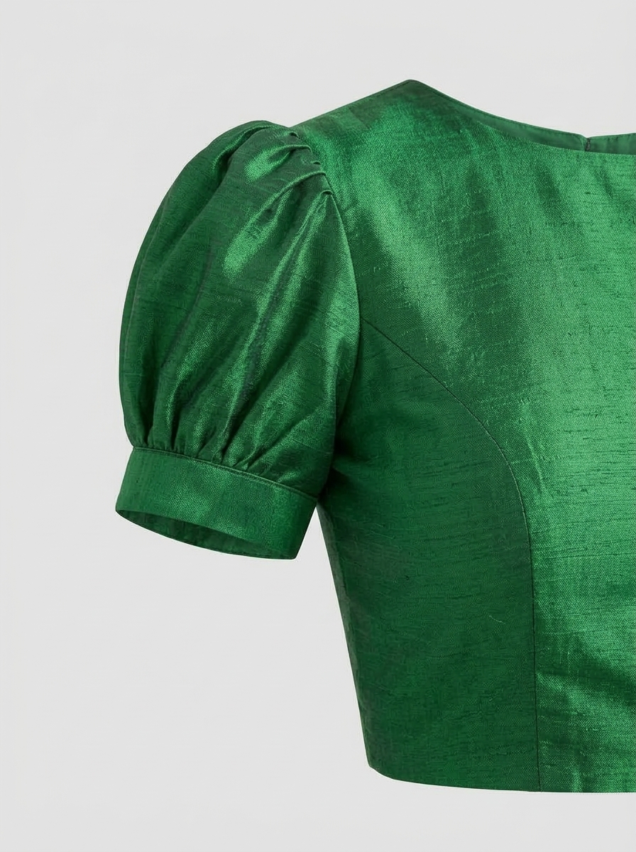 Detailed close-up of emerald green raw silk puffed sleeve shoulder gather and slub texture